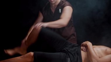 Stüdyoda kiropraktik seansı. Müvekkilinin bacaklarıyla çalışan bir terapist. Kalça eklemini oynatıyor.