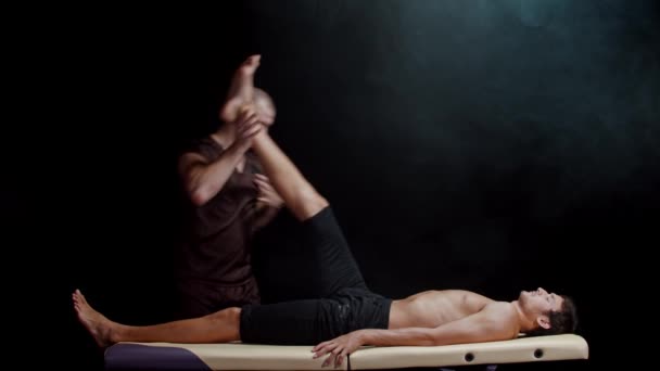 Chiropraktikus terápia a stúdióban - egy terapeuta, aki ügyfele lábaival dolgozik - a lábait a teste felé nyomja. — Stock videók