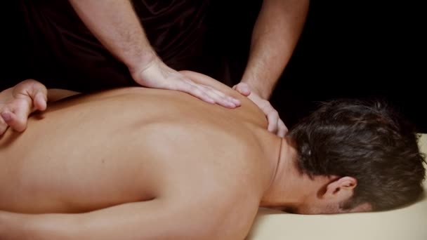 Chiropraktické sezení ve studiu - terapeut masírující čepel svého mužského klienta — Stock video