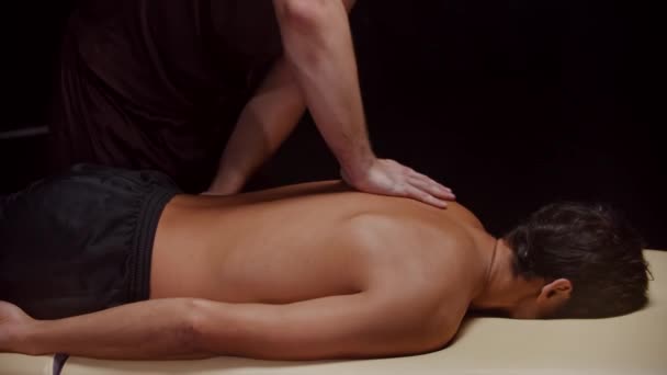 Sesión quiropráctica en el estudio - un terapeuta masajeando la espalda de su cliente masculino y empujándolo — Vídeos de Stock