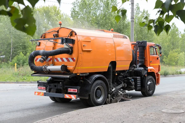 Gran máquina naranja limpia el asfalto con una barredora cerca de la acera — Foto de Stock