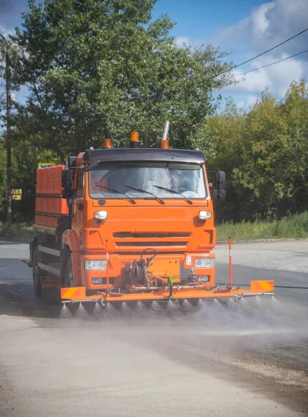 Gran máquina naranja limpia el asfalto con agua — Foto de Stock