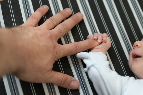 Ett nyfött barn som håller i sin fars finger — Stockfoto