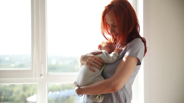 Ginger woman mother holding her baby and pats his back — Stock Video