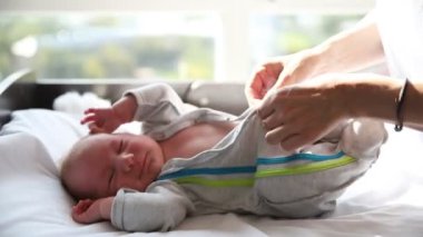 Anne, yeni doğmuş bebeğinin kostümünü ilikliyor.