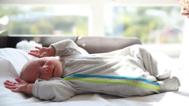 A little newborn baby fidgets in his sleeping in the baby cot — Stock Video