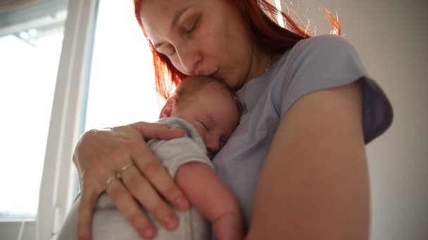 Ginger nő anya ölelés újszülött baba áll az ablaknál — Stock videók