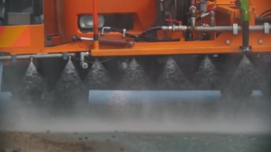 Büyük turuncu makine yönlü su akıntılarıyla asfaltı temizler.