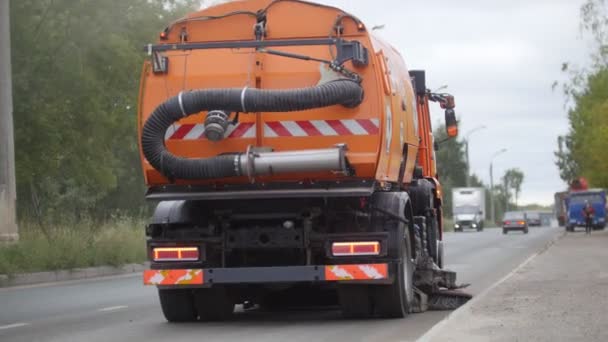 Большая оранжевая машина очищает асфальт очистителем - вид сзади — стоковое видео