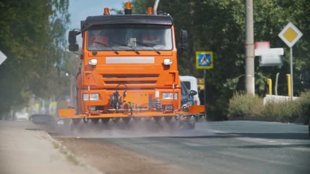Grote oranje machine ruimt het asfalt op met waterstromen — Stockvideo