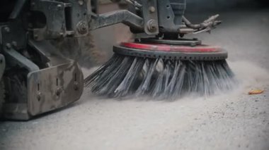 Makine tozdan bir süpürgeyle asfaltı temizler.