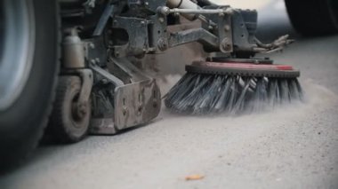 Makine beton tozundan süpürücüyle asfaltı temizler.