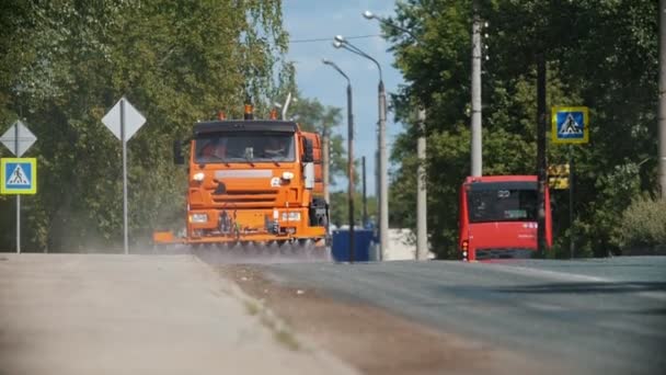 Stor orange maskine rydder asfalten ud af støv med vandløb – Stock-video