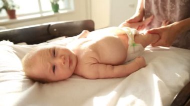 Anne yeni doğmuş bebeğine egzersiz yaptırıyor. Bacaklarıyla çalışıyor.