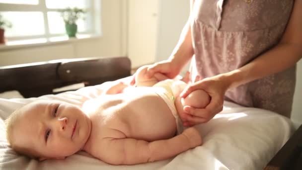 Мама делает упражнения для своего новорожденного ребенка - работает ногами — стоковое видео