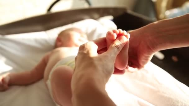 Ασκήσεις για μωρά - το μωρό ξαπλωμένο στο κρεβάτι και η μητέρα του να κάνει μασάζ στο πόδι — Αρχείο Βίντεο