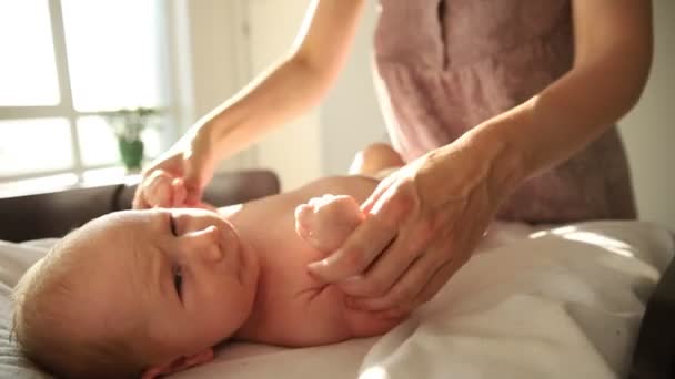 Oefeningen voor baby 's - de baby ligt op het bed en zijn moeder doet de oefeningen voor hem — Stockvideo