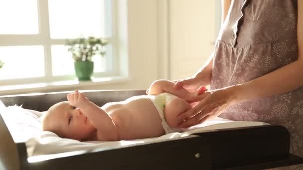 Упражнения для малышей - ребенок лежит на кровати, а его мать играет ногами — стоковое видео