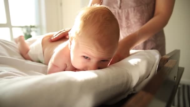 Bayi berbaring di perutnya dan ibunya menepuk dia di belakang — Stok Video