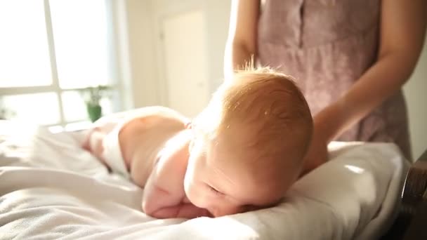 Μωρό σε μια πάνα ξαπλωμένο στο στομάχι του και η μητέρα του τον χαϊδεύει στην πλάτη — Αρχείο Βίντεο