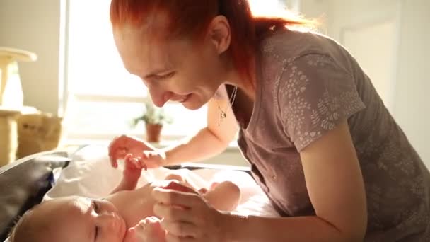 Τζίντζερ γυναίκα μητέρα παίζει με το μικρό νεογέννητο μωρό της και χαμογελά — Αρχείο Βίντεο