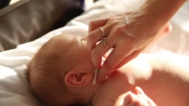 Az újszülött a hátán fekszik az ágyon, és a szülei kitörlik a nyakát. — Stock videók