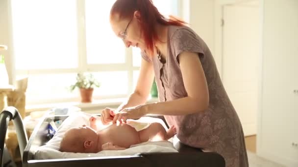 Любящая мать меняет подгузник своего малыша — стоковое видео