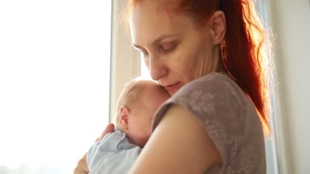 Τζίντζερ γυναίκα κρατάει το μωρό της και το χαϊδεύει. — Αρχείο Βίντεο