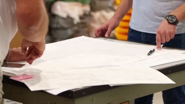 Mannen architecten staan boven het plan op het papier en wijzen ernaar. — Stockvideo