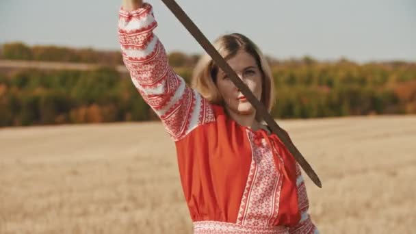 Mulher de vestido tradicional vermelho brincando com uma espada ao ar livre — Vídeo de Stock