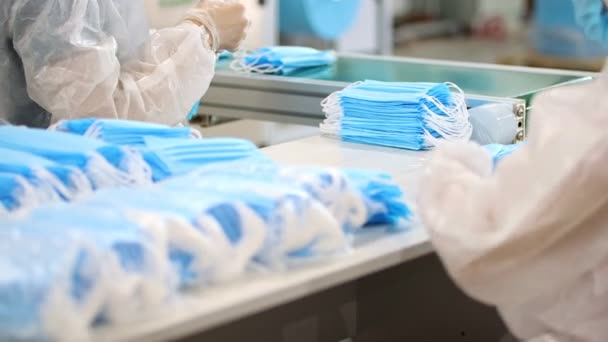 Průmyslová výroba lékařských masek - pracovníci balící masky na hromádky — Stock video