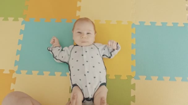 Mère jouant avec les jambes de son bébé alors qu'il est couché sur le dos — Video