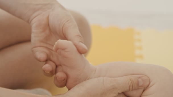 Мати робить ніжні вправи з маленькою ногою своєї дитини — стокове відео