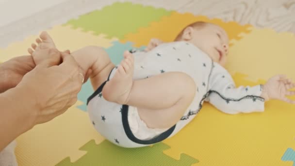 Мама робить ніжний масаж з маленькою ногою своєї дитини — стокове відео