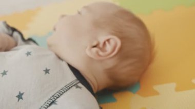 Küçük bebek sırtüstü yatar ve yuvarlanır