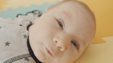 Küçük bebek sırtüstü uzanıp kameraya bakıyor.