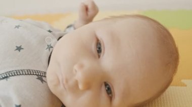 Küçük bebek sırt üstü uzanıyor ve kameranın arkasına bakıyor.