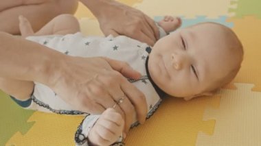 Bebek sırtüstü yatarken annesi onu okşuyor.