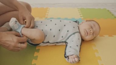 Anne yeni doğmuş bebeğinin ayaklarına çorap giydiriyor.