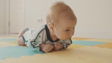 Küçük bebek paspasın üzerinde sürünüyor.