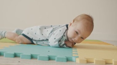 Pastel paspasın üzerinde karnının üstünde yatan küçük bebek.