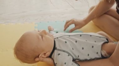 Anne bebeğiyle oynuyor, onunla oynuyor ve yüzünü pamukla siliyor.