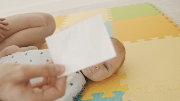 Mãe fazendo exercícios com seu bebê - fazendo-o seguir um pedaço de papel com os olhos — Vídeo de Stock