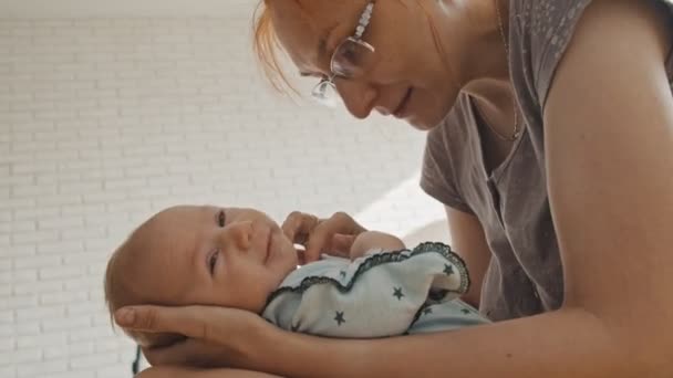 En mor vaggar sitt barn i sina armar — Stockvideo