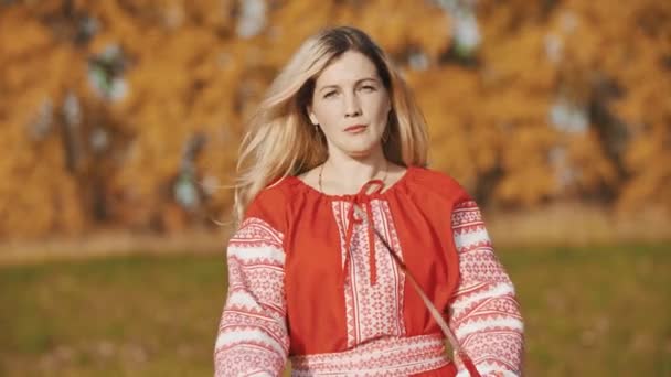 Feisty vrouw in rode kleren staan op het veld met haar zwaarden cross wise — Stockvideo