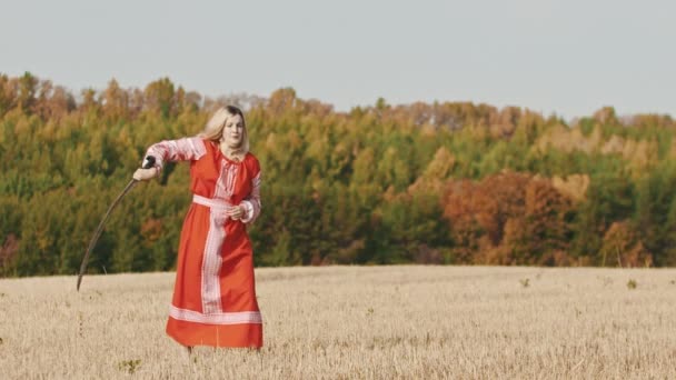 Zadziorna kobieta w czerwonej sukience trenująca na boisku - pociągi z mieczem i kończące pozowanie — Wideo stockowe
