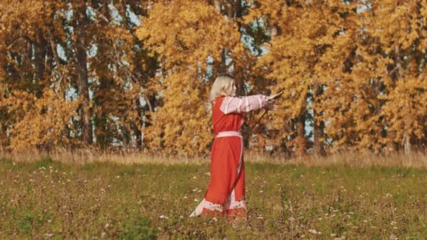 Feisty kvinna i röd nationell klänning roterande ett svärd runt sig själv — Stockvideo