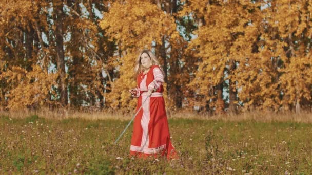 Middeleeuws concept - vrouw in rode nationale jurk die een zwaard om zich heen draait — Stockvideo