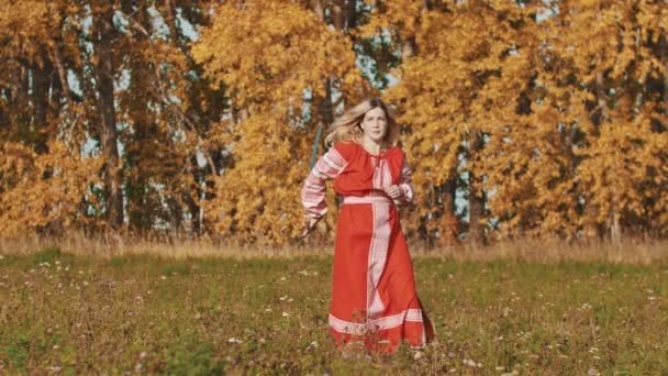 Middeleeuws concept - vrouw in rode nationale lange jurk die een zwaard omhoog gooit en vangt — Stockvideo