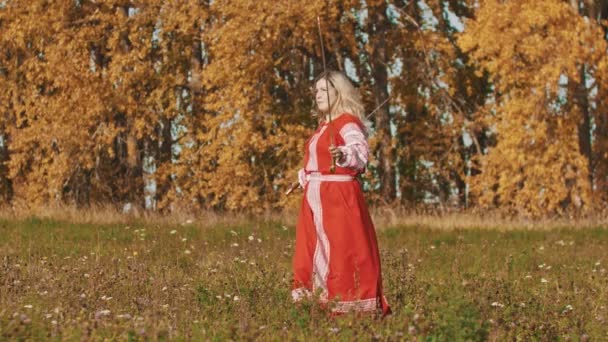 Ortaçağ konsepti - kırmızı uzun elbiseli kadın ustaca kılıç kullanıyor — Stok video
